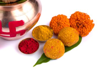 Hindistan cevizli bakır Kalaş, mango yaprağı Haldi, kumkum ve beyaz arka planda kadife çiçeği süslemesi olan tatlılar. Hindu pujası için gereklidir..