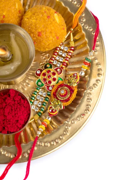 Indian Festival: Rakhi z ziarnami ryżu, kumkum, słodycze i diya na talerzu z eleganckim Rakhi. Tradycyjna indyjska opaska na nadgarstek, która jest symbolem miłości między braćmi i siostrami — Zdjęcie stockowe