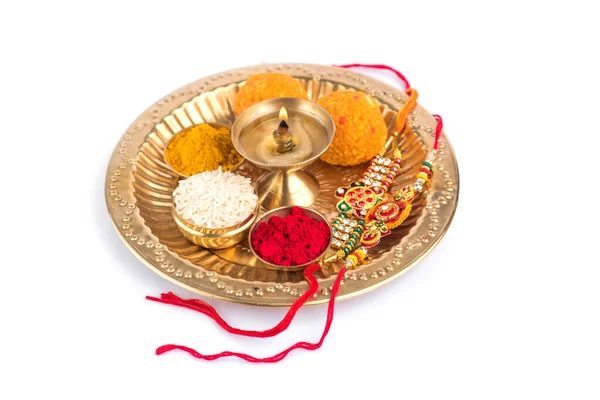 Festival indien : Rakhi aux grains de riz, kumkum, bonbons et diya sur assiette avec un élégant Rakhi. Un bracelet traditionnel indien qui symbolise l'amour entre frères et sœurs — Photo