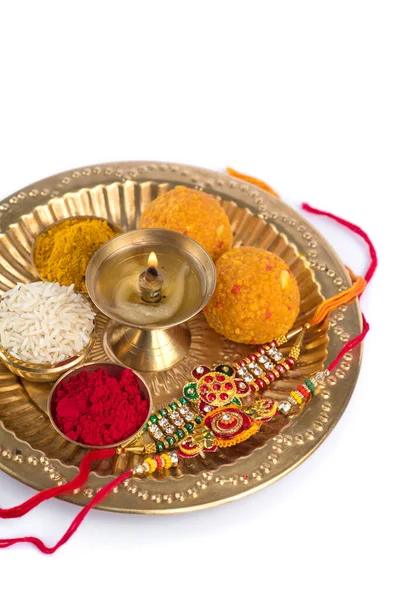 インド祭:お米、クムク、お菓子、ディヤを盛り付けた、上品なラキのラキ。兄弟姉妹間の愛の象徴である伝統的なインドの手首バンド — ストック写真