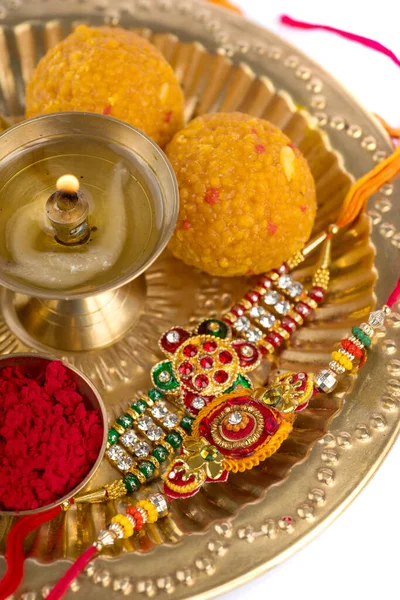Festival India: Rakhi dengan biji-bijian beras, kumkum, permen dan diya di atas piring dengan Rakhi yang elegan. Sebuah gelang tradisional India yang merupakan simbol cinta antara Brothers dan Sisters — Stok Foto
