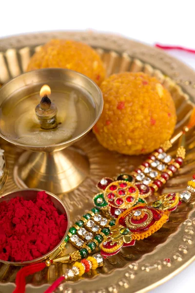 Indian Festival: Rakhi z ziarnami ryżu, kumkum, słodycze i diya na talerzu z eleganckim Rakhi. Tradycyjna indyjska opaska na nadgarstek, która jest symbolem miłości między braćmi i siostrami — Zdjęcie stockowe