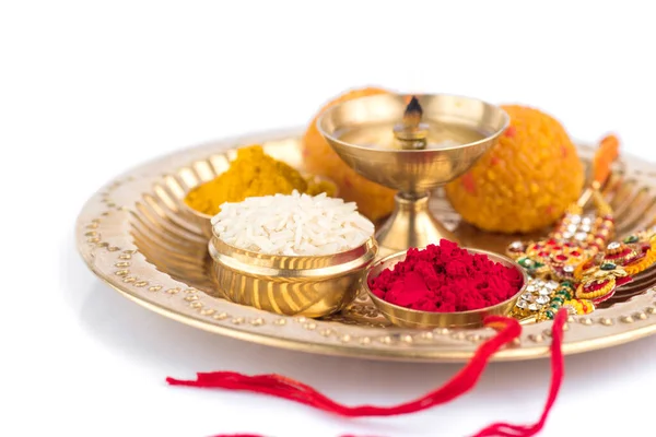 Festival indien : Rakhi aux grains de riz, kumkum, bonbons et diya sur assiette avec un élégant Rakhi. Un bracelet traditionnel indien qui symbolise l'amour entre frères et sœurs — Photo