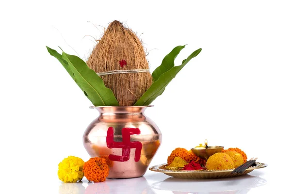 Hindistan cevizi ve mango yaprağıyla bakır Kalaş ve beyaz arka planda çiçek desenli diya, kumkum ve tatlılar ile pooja thali. Hindu pujası için gerekli..
