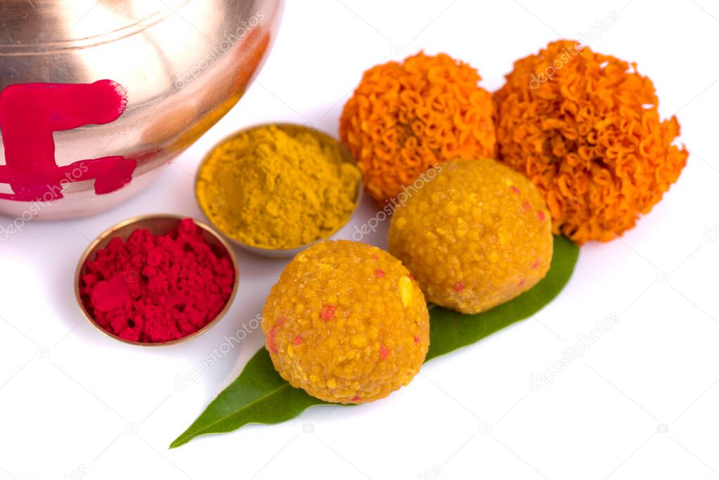 Copper Kalash with coconut, mango leaf, Haldi, kumkum and sweets with marigold flower decoration on a white background. Essential in Hindu puja.