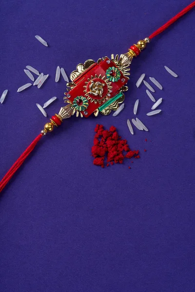 Raksha Bandhan : Rakhi with rice grains and kumkum. An Indian festive background. Traditional Indian wrist band which is a symbol of love between Brothers and Sisters.