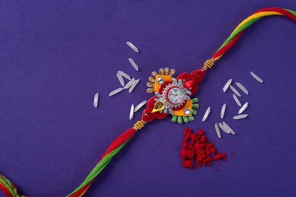 Raksha Bandhan : Rakhi with rice grains and kumkum. An Indian festive background. Traditional Indian wrist band which is a symbol of love between Brothers and Sisters.