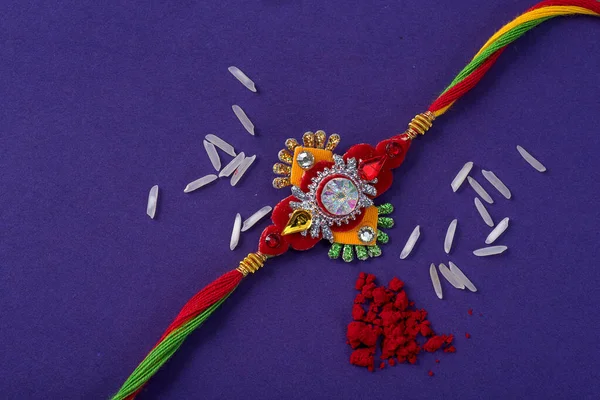 Raksha Bandhan : Rakhi with rice grains and kumkum. An Indian festive background. Traditional Indian wrist band which is a symbol of love between Brothers and Sisters.