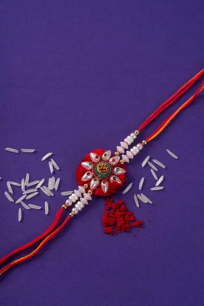 Raksha Bandhan : Rakhi with rice grains and kumkum. An Indian festive background. Traditional Indian wrist band which is a symbol of love between Brothers and Sisters.