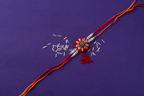 Raksha Bandhan : Rakhi with rice grains and kumkum. An Indian festive background. Traditional Indian wrist band which is a symbol of love between Brothers and Sisters.