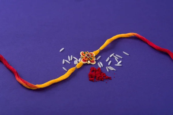 Raksha Bandhan : Rakhi with rice grains and kumkum. An Indian festive background. Traditional Indian wrist band which is a symbol of love between Brothers and Sisters.