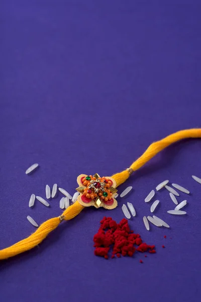 Raksha Bandhan : Rakhi with rice grains and kumkum. An Indian festive background. Traditional Indian wrist band which is a symbol of love between Brothers and Sisters.