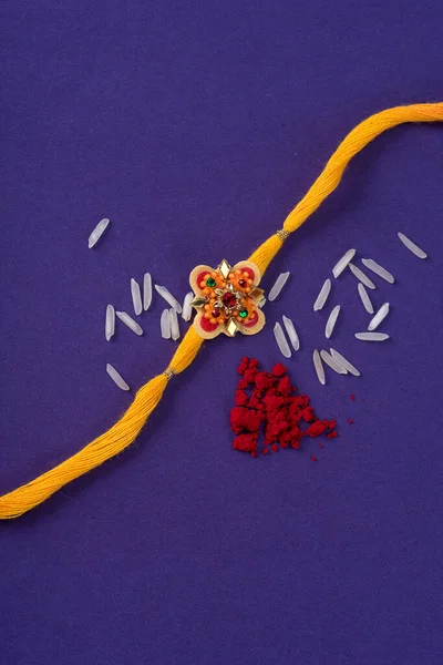 Raksha Bandhan : Rakhi with rice grains and kumkum. An Indian festive background. Traditional Indian wrist band which is a symbol of love between Brothers and Sisters.