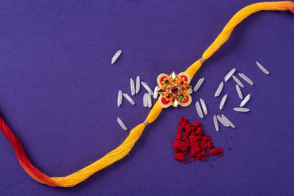 Raksha Bandhan : Rakhi with rice grains and kumkum. An Indian festive background. Traditional Indian wrist band which is a symbol of love between Brothers and Sisters.