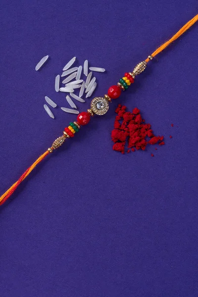 Raksha Bandhan : Rakhi with rice grains and kumkum. An Indian festive background. Traditional Indian wrist band which is a symbol of love between Brothers and Sisters.