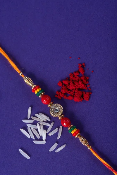 Raksha Bandhan : Rakhi with rice grains and kumkum. An Indian festive background. Traditional Indian wrist band which is a symbol of love between Brothers and Sisters.