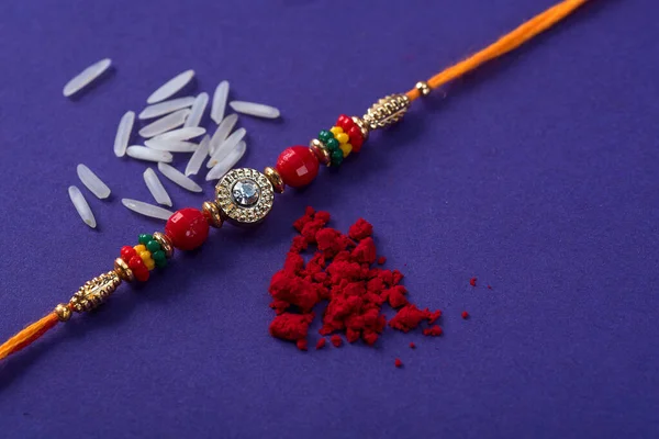 Raksha Bandhan : Rakhi with rice grains and kumkum. An Indian festive background. Traditional Indian wrist band which is a symbol of love between Brothers and Sisters.