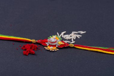 Raksha Bandhan: Siyah zemin üzerinde pirinç taneleri ve kumkum bulunan Rakhi, Kardeşler ve Kardeşler arasındaki aşkın sembolü olan geleneksel Hint bilekliği.