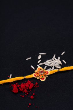 Raksha Bandhan: Siyah zemin üzerinde pirinç taneleri ve kumkum bulunan Rakhi, Kardeşler ve Kardeşler arasındaki aşkın sembolü olan geleneksel Hint bilekliği.