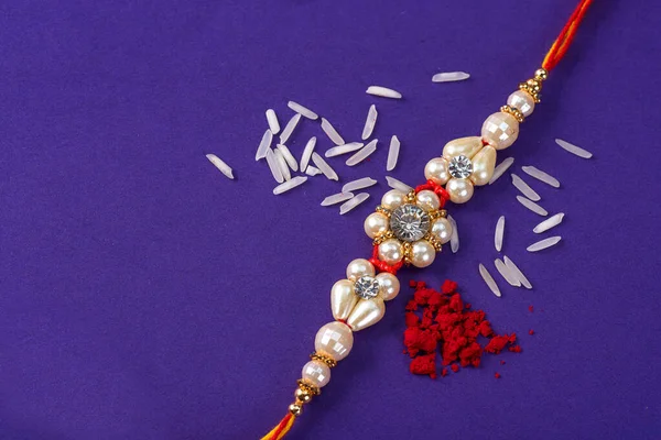 Raksha Bandhan : Rakhi with rice grains and kumkum. An Indian festive background. Traditional Indian wrist band which is a symbol of love between Brothers and Sisters.