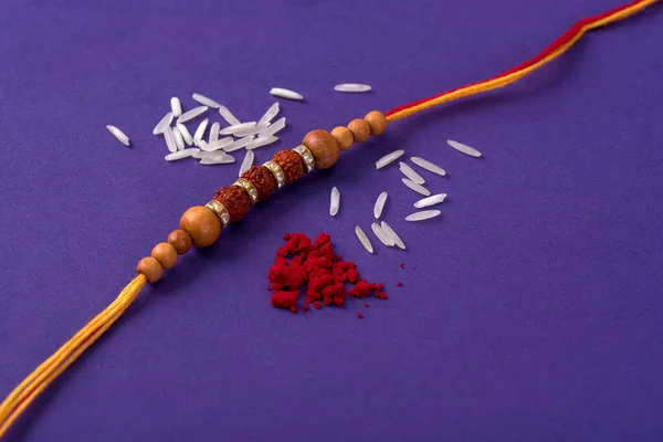 Raksha Bandhan : Rakhi with rice grains and kumkum. An Indian festive background. Traditional Indian wrist band which is a symbol of love between Brothers and Sisters.