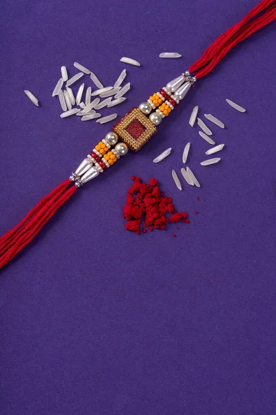 Raksha Bandhan : Rakhi with rice grains and kumkum. An Indian festive background. Traditional Indian wrist band which is a symbol of love between Brothers and Sisters.