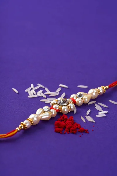 Raksha Bandhan : Rakhi with rice grains and kumkum. An Indian festive background. Traditional Indian wrist band which is a symbol of love between Brothers and Sisters.