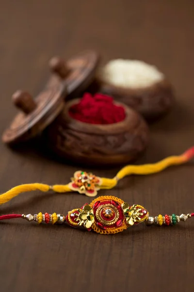 เทศกาลอินเดีย: พื้นหลังราชาบันดานกับ Rakhi, ข้าวธัญพืชและกุมมะที่สง่างาม วงข้อมืออินเดียแบบดั้งเดิมซึ่งเป็นสัญลักษณ์ของความรักระหว่างพี่น้องและพี่น้อง . — ภาพถ่ายสต็อก