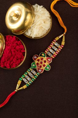 Raksha Bandhan 'ın arkaplanı zarif bir Rakhi, pirinç taneleri ve Kumkum. Geleneksel Hint bilekliği Kardeşler ve Kız Kardeşler arasındaki aşkın sembolüdür..
