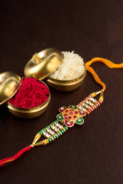 Raksha Bandhan background with an elegant Rakhi, Rice Grains and Kumkum. A traditional Indian wrist band which is a symbol of love between Brothers and Sisters. — Stock Photo, Image