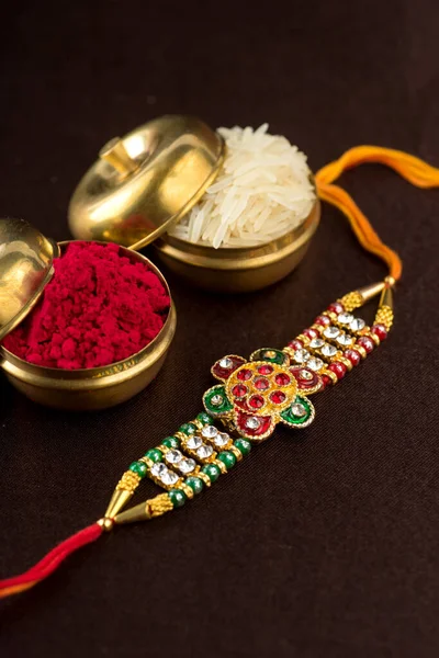Raksha Bandhan háttér elegáns Rakhi, Rice Grains és Kumkum. Egy tradicionális indiai csuklópánt, ami a testvérek és testvérek közötti szeretet szimbóluma.. — Stock Fotó