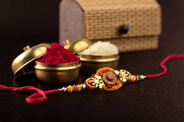Raksha Bandhan 'ın arkaplanı zarif bir Rakhi, pirinç taneleri ve Kumkum. Geleneksel Hint bilekliği Kardeşler ve Kız Kardeşler arasındaki aşkın sembolüdür..