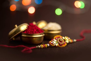 Raksha Bandhan 'ın arkaplanı zarif bir Rakhi, pirinç taneleri ve Kumkum. Geleneksel Hint bilekliği Kardeşler ve Kız Kardeşler arasındaki aşkın sembolüdür..