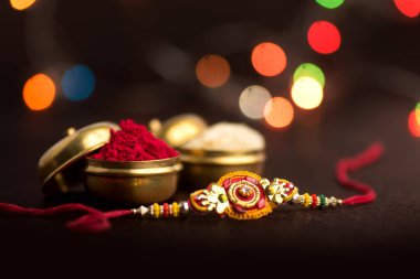 Raksha Bandhan 'ın arkaplanı zarif bir Rakhi, pirinç taneleri ve Kumkum. Geleneksel Hint bilekliği Kardeşler ve Kız Kardeşler arasındaki aşkın sembolüdür..