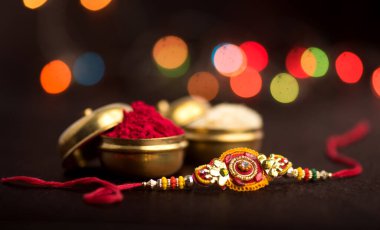 Raksha Bandhan 'ın arkaplanı zarif bir Rakhi, pirinç taneleri ve Kumkum. Geleneksel Hint bilekliği Kardeşler ve Kız Kardeşler arasındaki aşkın sembolüdür..