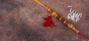 Raksha Bandhan: Taş zemin üzerinde pirinç taneleri ve kumkum bulunan Rakhi, Kardeşler ve Kardeşler arasındaki aşkın sembolü olan geleneksel Hint bilekliği.