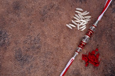 Raksha Bandhan: Taş zemin üzerinde pirinç taneleri ve kumkum bulunan Rakhi, Kardeşler ve Kardeşler arasındaki aşkın sembolü olan geleneksel Hint bilekliği.