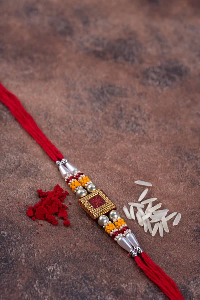 Raksha Bandhan: Rakhi med ris korn och kumkum på sten bakgrund, Traditionell indisk handled band som är en symbol för kärlek mellan bröder och systrar. — Stockfoto