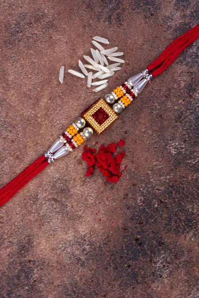 Raksha Bandhan: Rakhi dengan biji-bijian padi dan kumkum di latar belakang batu, gelang tangan tradisional India yang merupakan simbol cinta antara Brothers dan Sisters . — Stok Foto