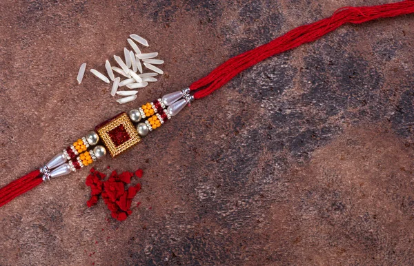 Ракша Бандхан: Ракхи с рисовыми зернами и кумкумом на каменном фоне, традиционная индийская группа запястья, которая является символом любви между братьями и сестрами . — стоковое фото