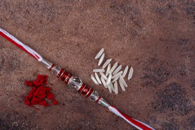 Raksha Bandhan: Taş zemin üzerinde pirinç taneleri ve kumkum bulunan Rakhi, Kardeşler ve Kardeşler arasındaki aşkın sembolü olan geleneksel Hint bilekliği.