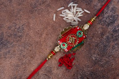 Raksha Bandhan: Taş zemin üzerinde pirinç taneleri ve kumkum bulunan Rakhi, Kardeşler ve Kardeşler arasındaki aşkın sembolü olan geleneksel Hint bilekliği.