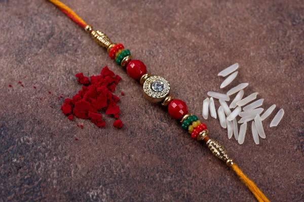 Raksha Bandhan: Rakhi cu boabe de orez și kumkum pe fundal de piatră, banda tradițională de încheietură a mâinii indiene, care este un simbol al iubirii dintre frați și surori . — Fotografie, imagine de stoc