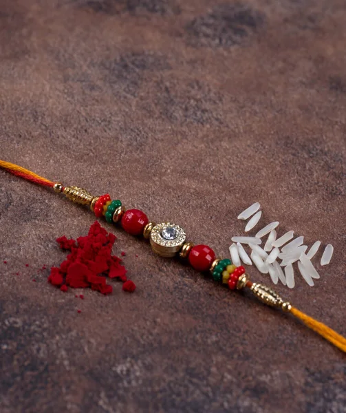 Raksha Bandhan: Rakhi with rice grains and kumkum on stone background, Традиційний індійський зап'ясток гурт, який є символом любові між братами і сестрами. — стокове фото