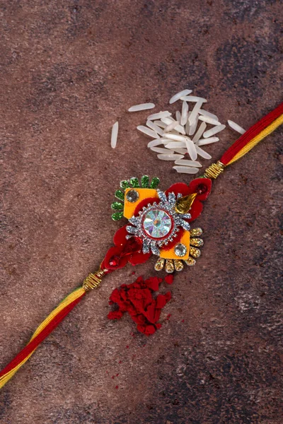 Raksha Bandhan: Rakhi with rice grains and kumkum on stone background, Традиційний індійський зап'ясток гурт, який є символом любові між братами і сестрами. — стокове фото