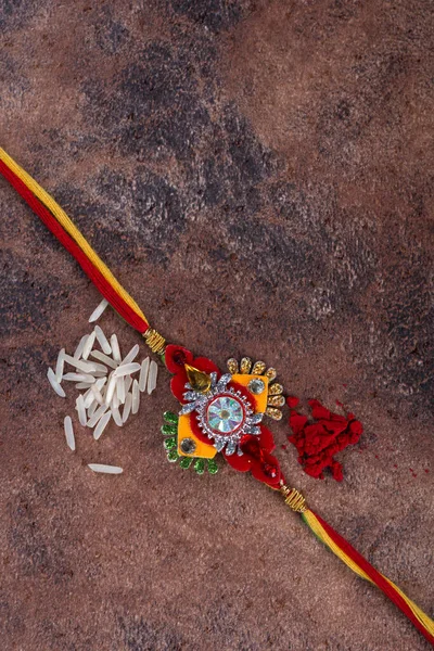 Raksha Bandhan: Rakhi with rice grains and kumkum on stone background, Традиційний індійський зап'ясток гурт, який є символом любові між братами і сестрами. — стокове фото