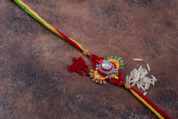 Raksha Bandhan: Taş zemin üzerinde pirinç taneleri ve kumkum bulunan Rakhi, Kardeşler ve Kardeşler arasındaki aşkın sembolü olan geleneksel Hint bilekliği. — Stok fotoğraf
