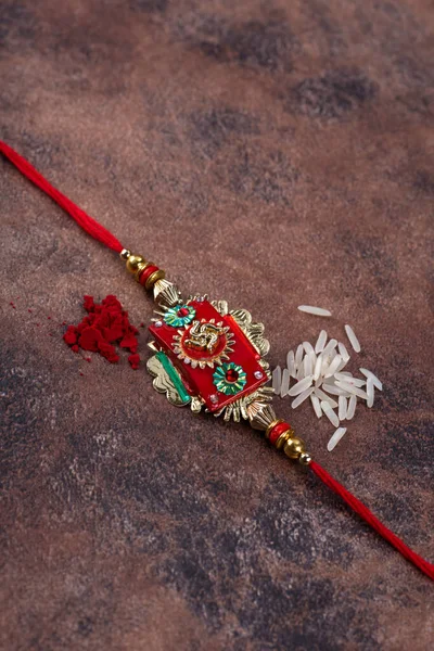 Raksha Bandhan: Rakhi com grãos de arroz e kumkum sobre fundo de pedra, tradicional pulseira indiana que é um símbolo de amor entre irmãos e irmãs . — Fotografia de Stock