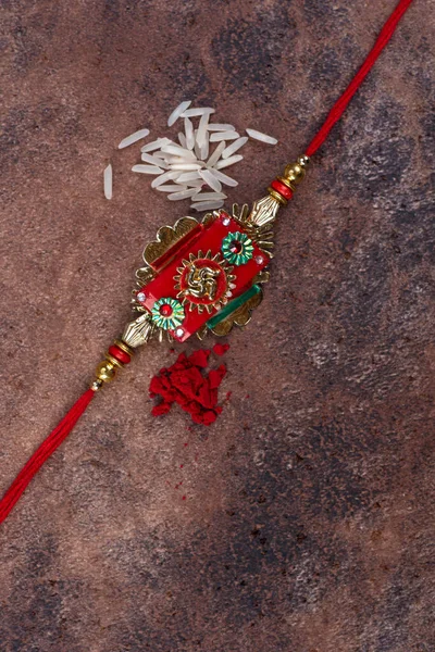 Raksha Bandhan : Rakhi with rice grains and kumkum on stone background, Traditional Indian wrist band which is a symbol of love between Brothers and Sisters. — Stock Photo, Image