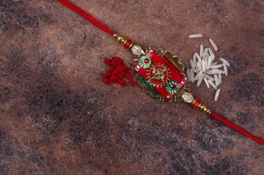 Raksha Bandhan: Taş zemin üzerinde pirinç taneleri ve kumkum bulunan Rakhi, Kardeşler ve Kardeşler arasındaki aşkın sembolü olan geleneksel Hint bilekliği.
